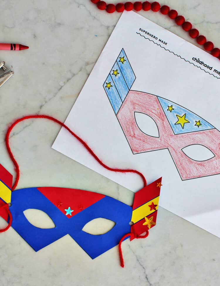cut out paper mask with yarn string next to a coloring page of a superhero mask for kids.
