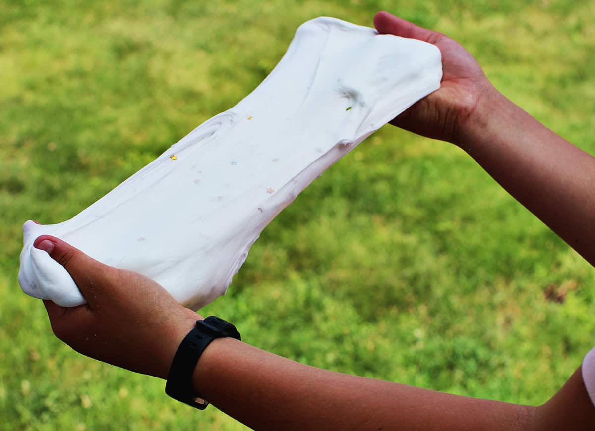 Hands stretching white fluffy slime.