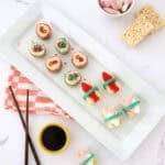 sushi candy madefrom rice krispie treats and other candies next to chop sticks and a small bowl of chocolate syrup.