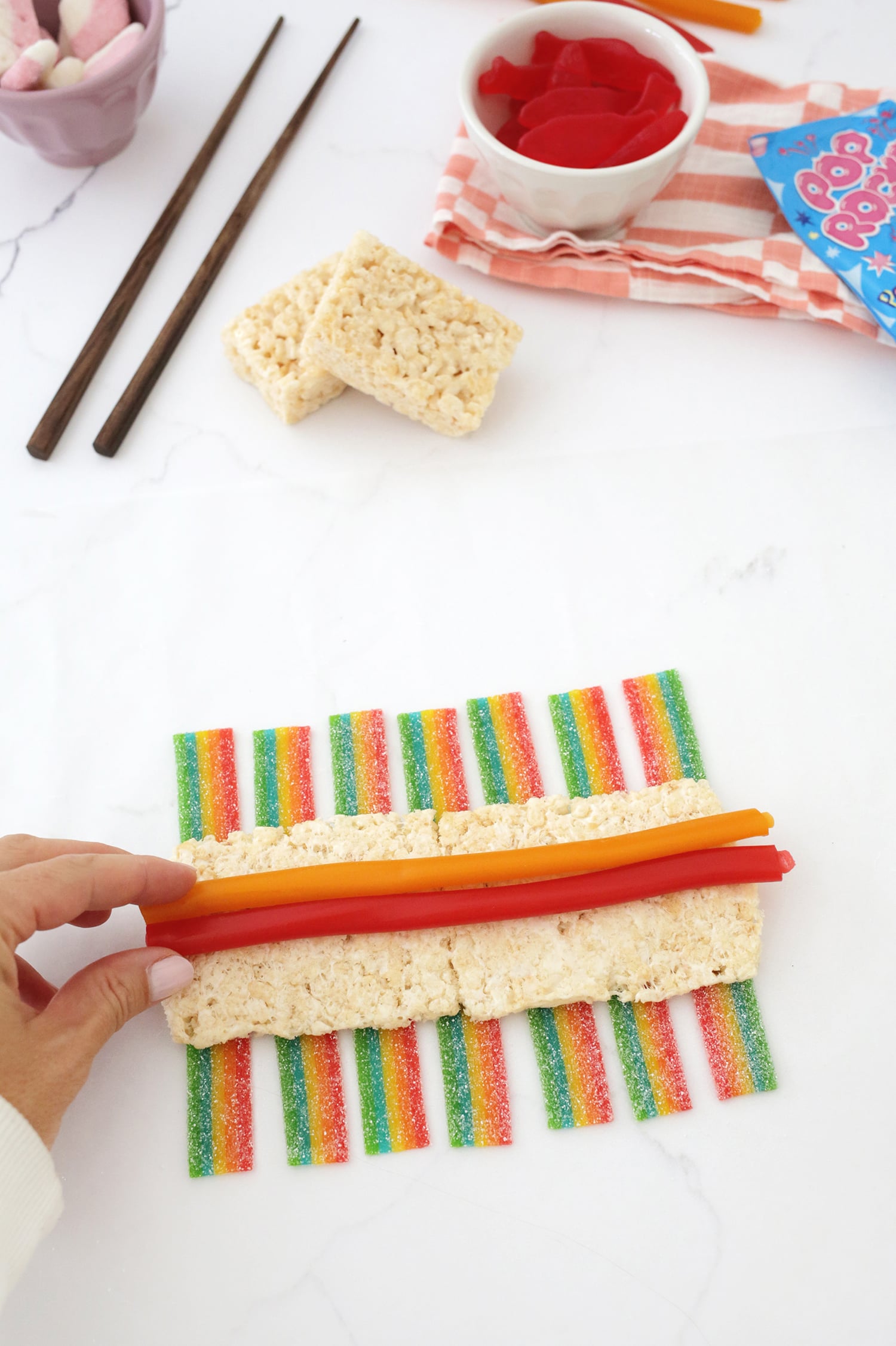jolly rancher ropes being added on top of rice kripsies and airheads to make a candy sushi roll.