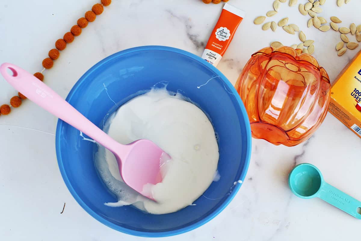 Baking soda, school glue and contact solution combined in a blue bowl to make slime.