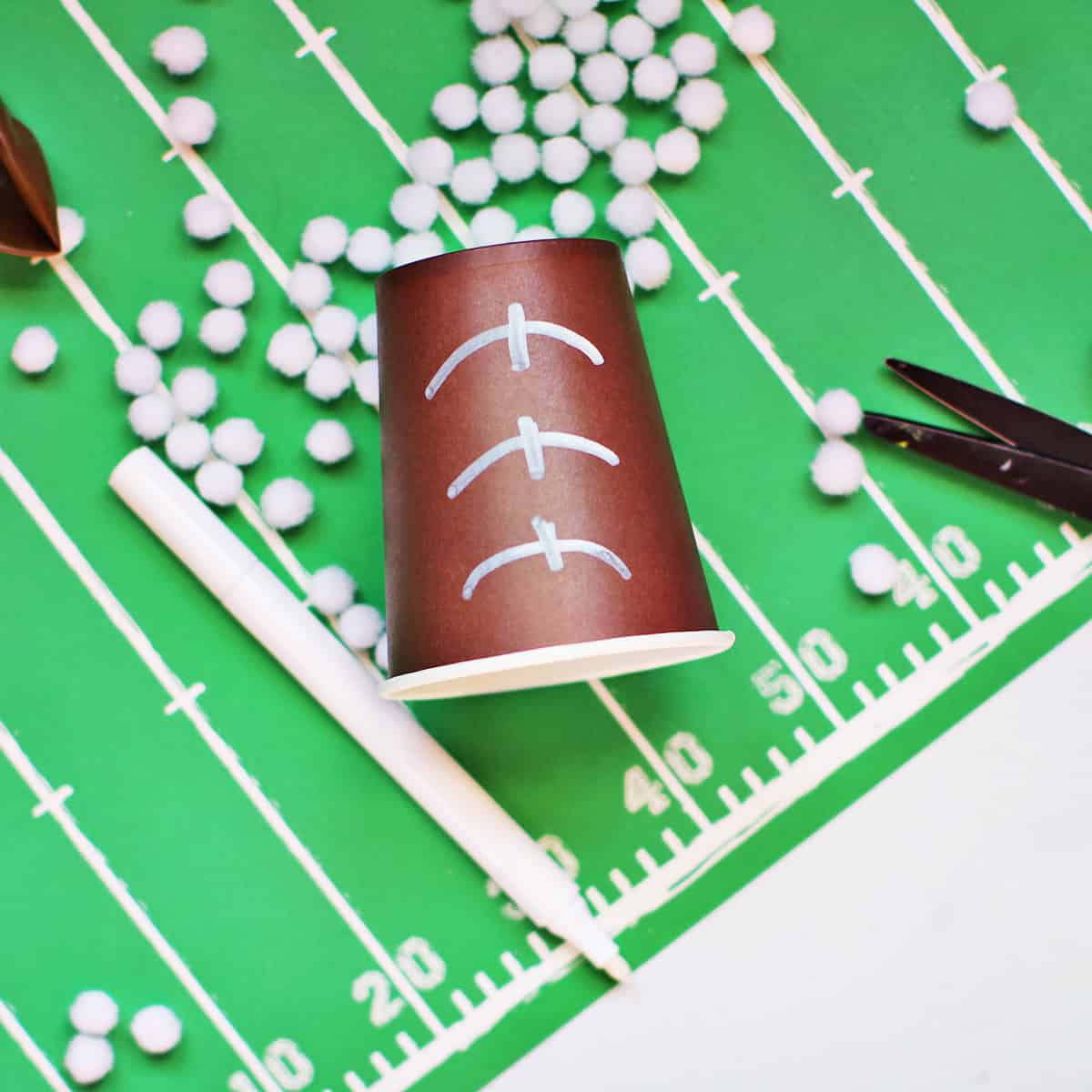 A brown cup with white lines drawn on it to look like a football.