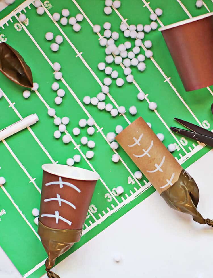 pom pom shooters made with brown cups and brown balloons to look like footballs on a football field placemat.