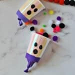 cup with a balloon wrapped around the bottom to shoot out pom poms and decorated to look like a ghost.