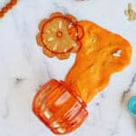 pumpkin slime with pumpkin seeds coming out of an orange plastic pumpkin container