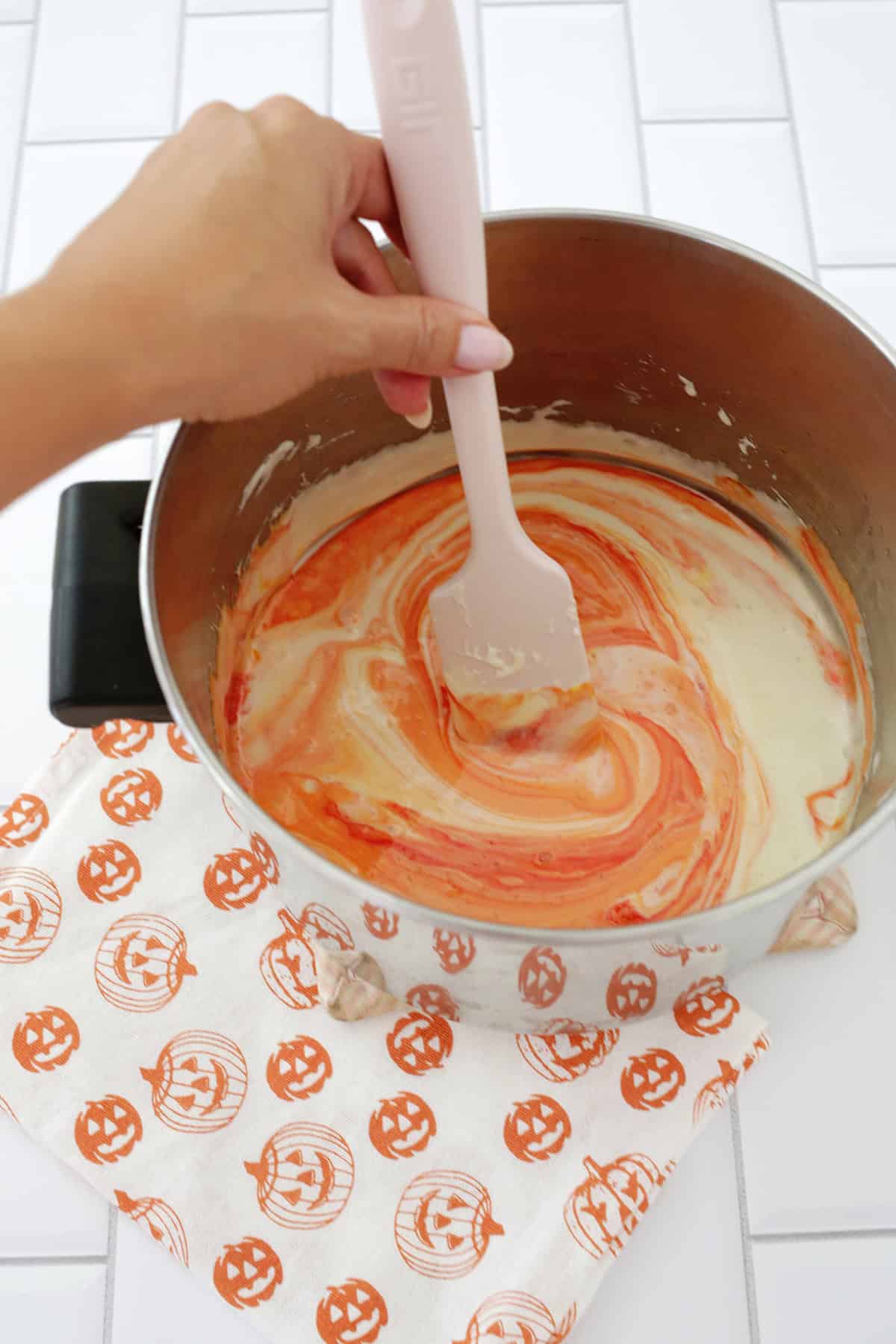 adding food coloring to melted butter and marshmallows in a pot.