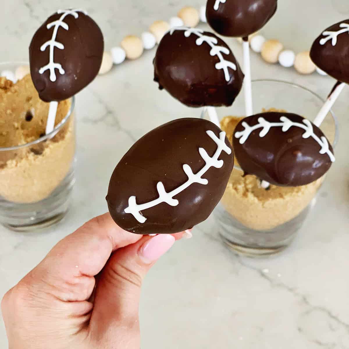 Hand holding a cake pop decorated to look like a football.