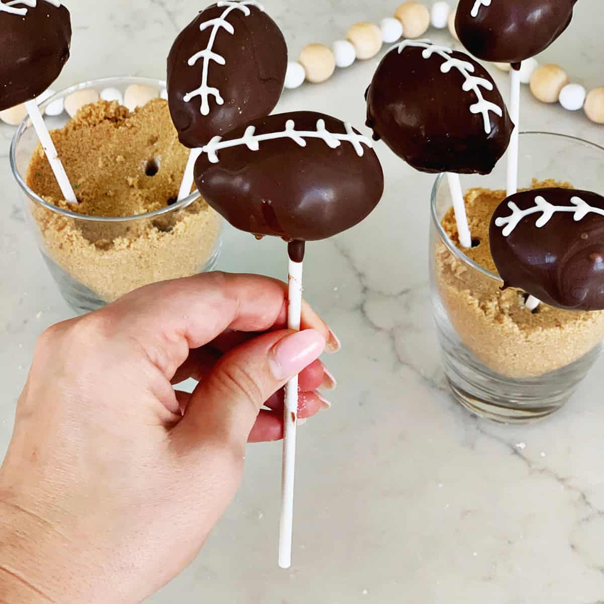 Hand holding a cake pop decorated to look like a football.