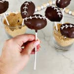 Hand holding a cake pop decorated to look like a football.